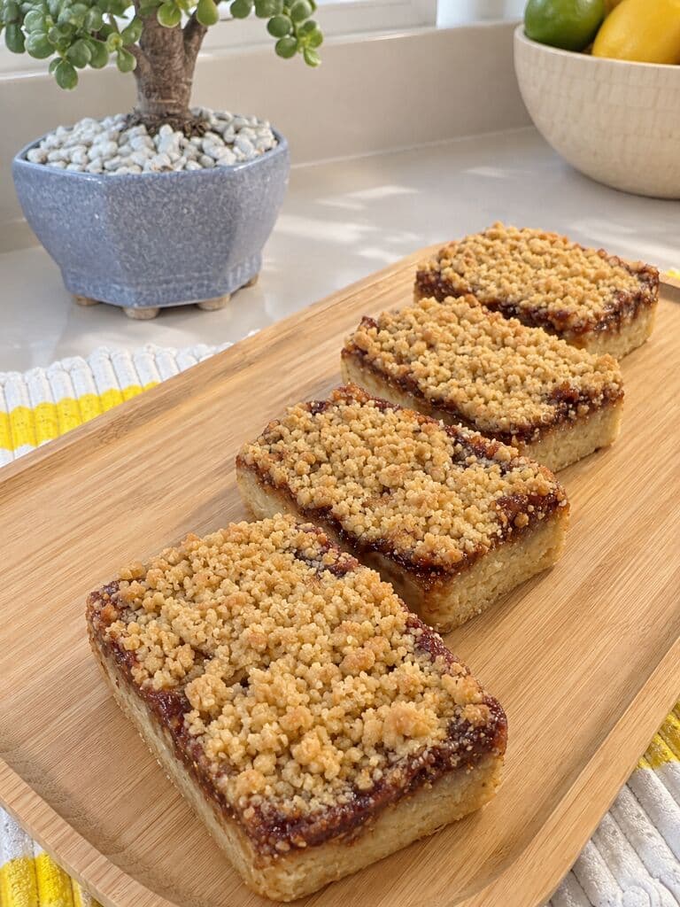 Porciones de torta de manzana con capa de jalea y streusel, sobre una tabla de madera
